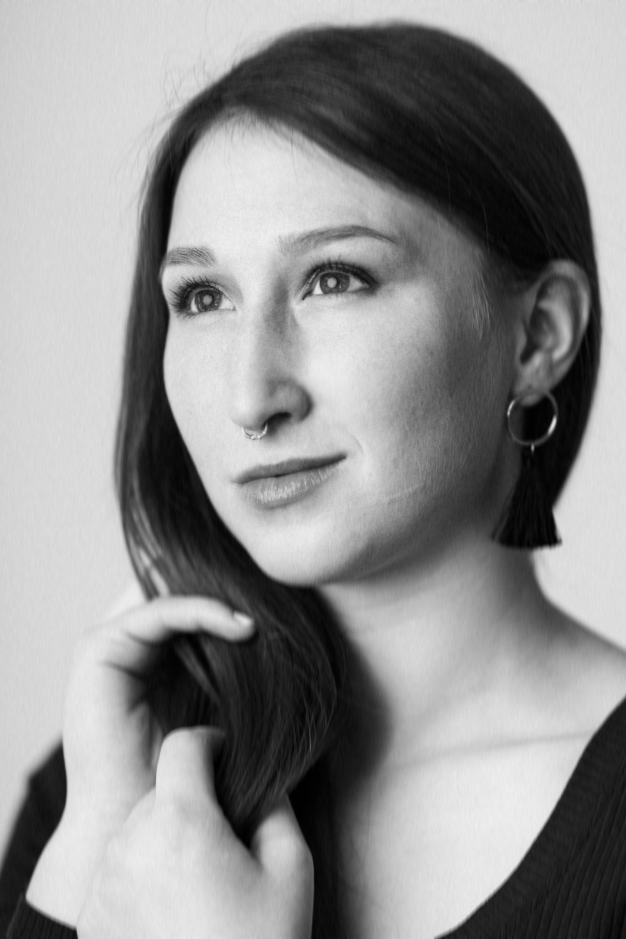 A woman with long hair adorned with earrings, exuding elegance and style in a captivating pose.