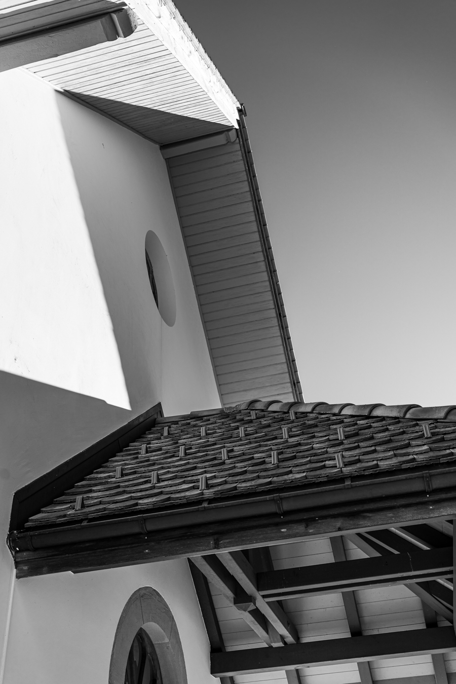 Close-up of a building corner showcasing contrasting architectural elements and textures in black and white against a clear sky.