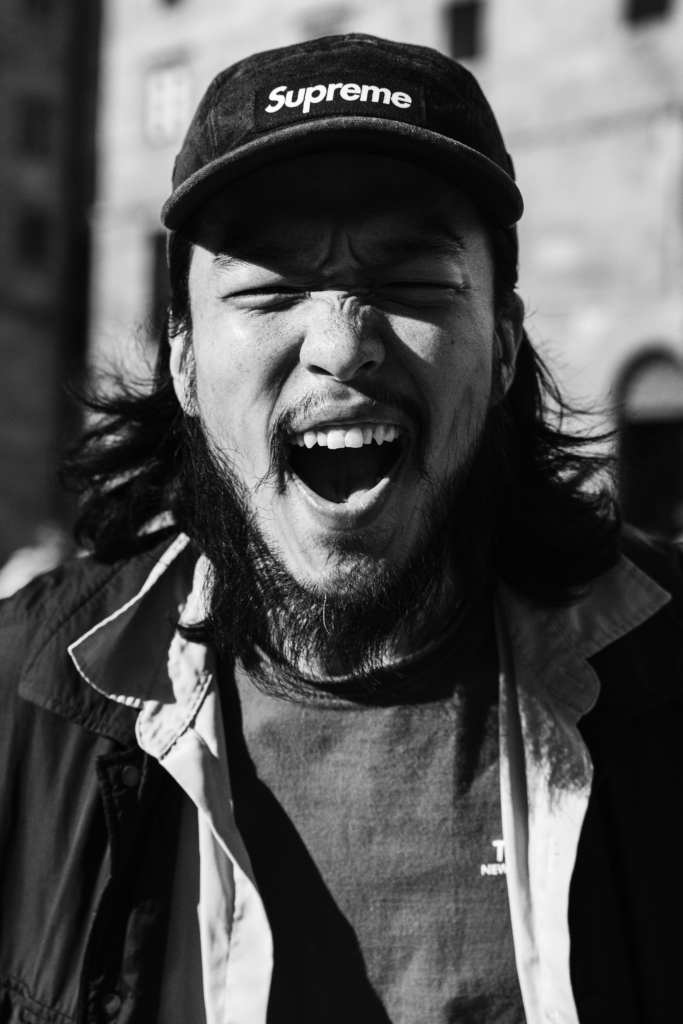 Portrait of a man outdoors wearing a hat and open-mouthed smile.