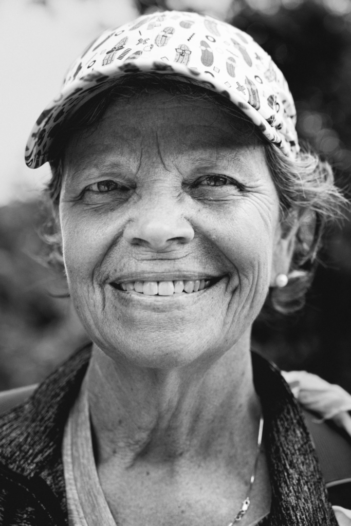 Portrait of a woman wearing a hat and a light jacket, smiling gently.
