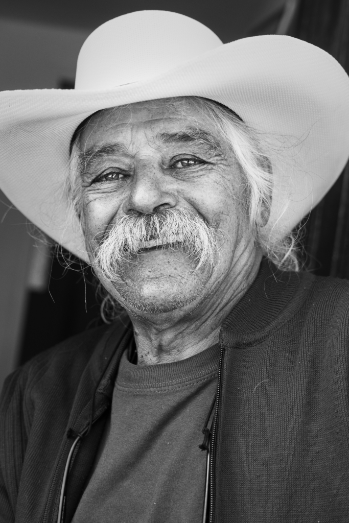 Portrait of an older man wearing a white cowboy hat.