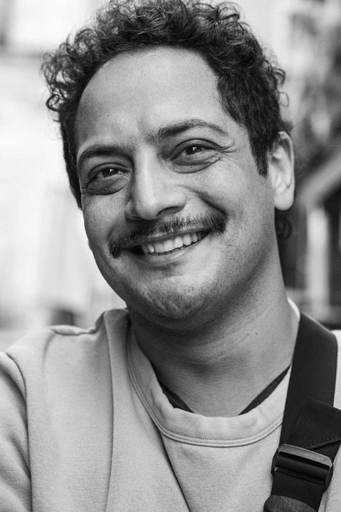 Portrait of a man with curly hair smiling.
