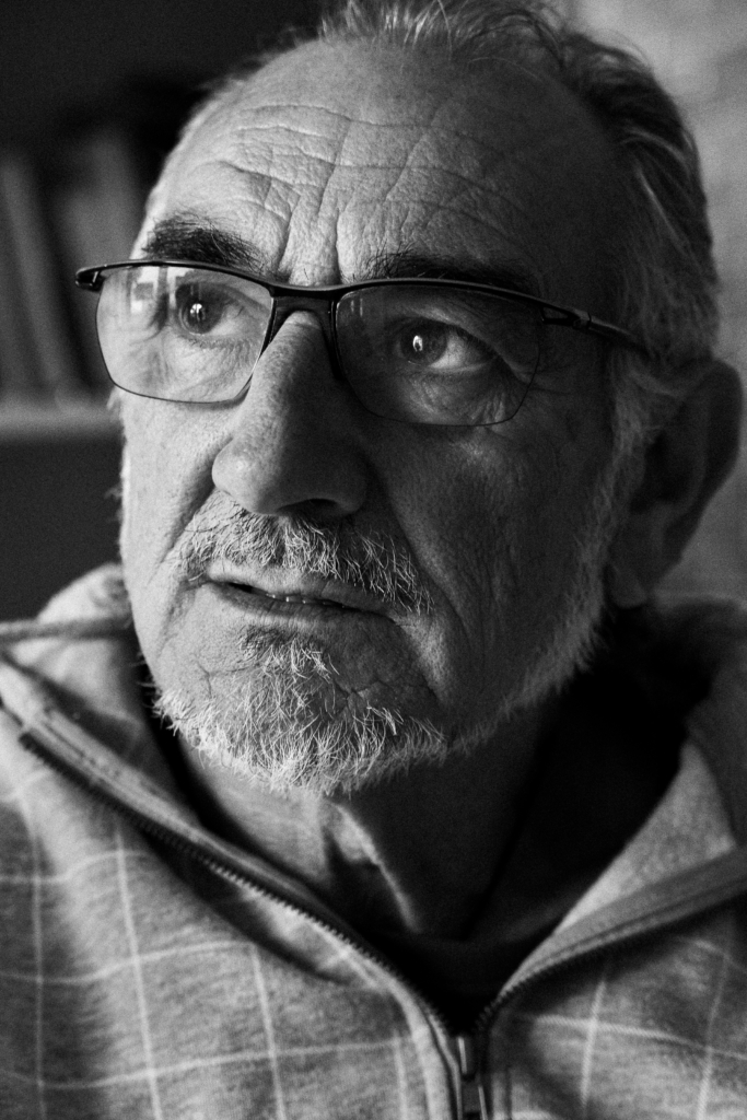 Portrait of a man wearing glasses and a hat, neutral expression.