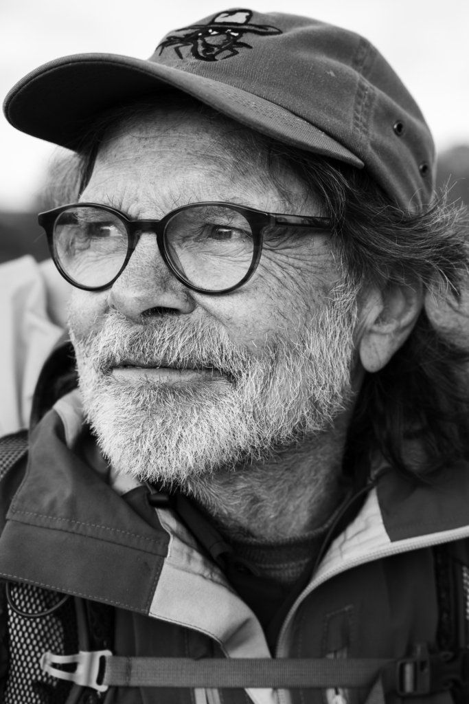 Portrait of a man with glasses and a cap, smiling.