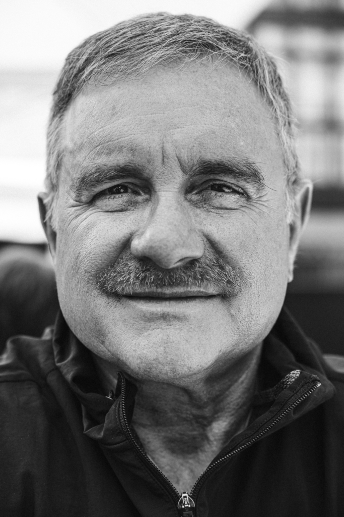 Portrait of a man with a mustache smiling warmly.