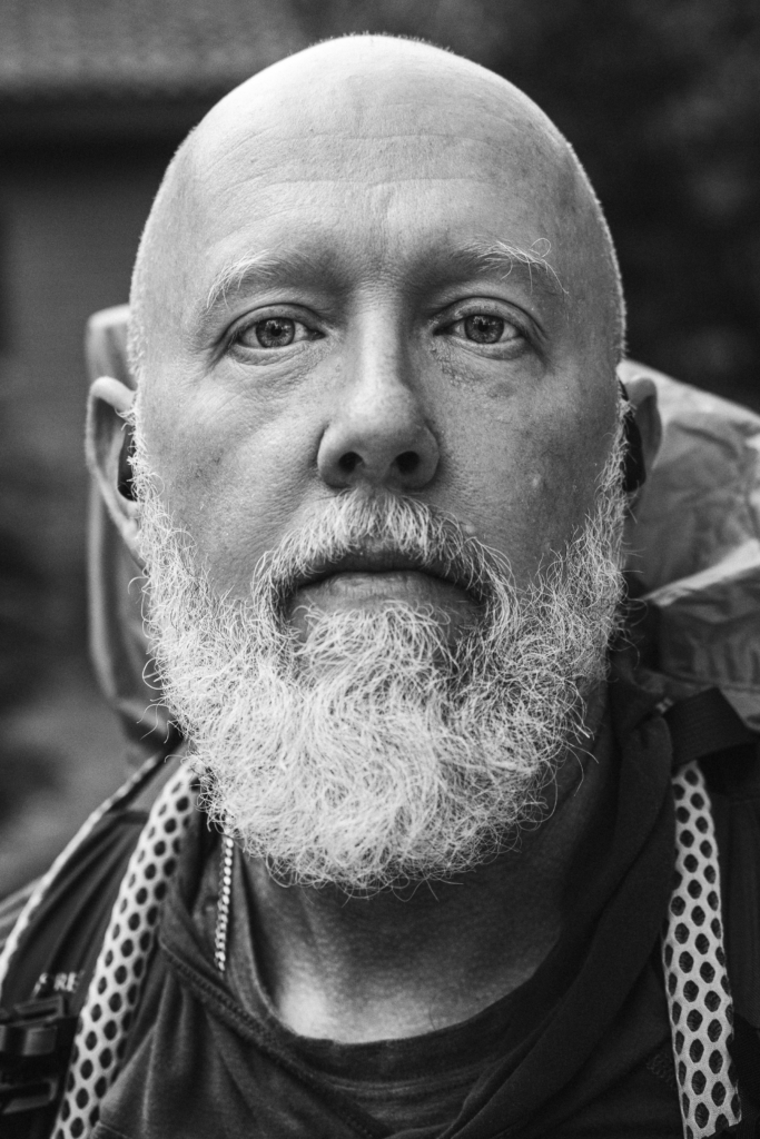 Portrait of a bearded man with a neutral expression, looking into the camera.