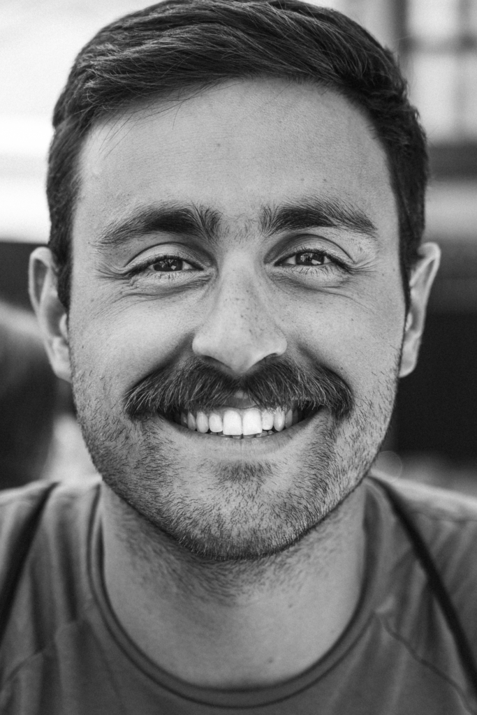 Portrait of a man with a mustache smiling warmly.